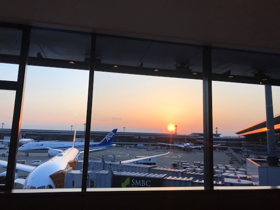 A panoramic view of multiple airplanes lined up at the airport terminal at sunset.