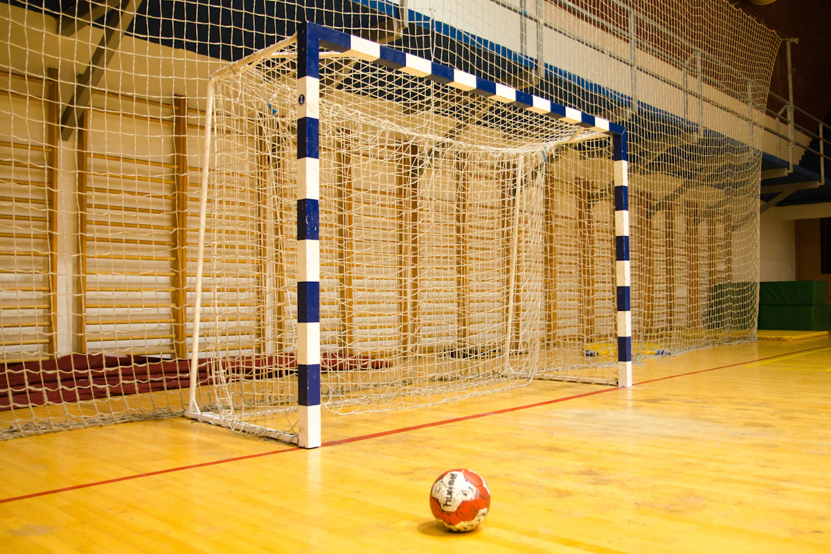 A player with a foot on a soccer ball on an indoor field