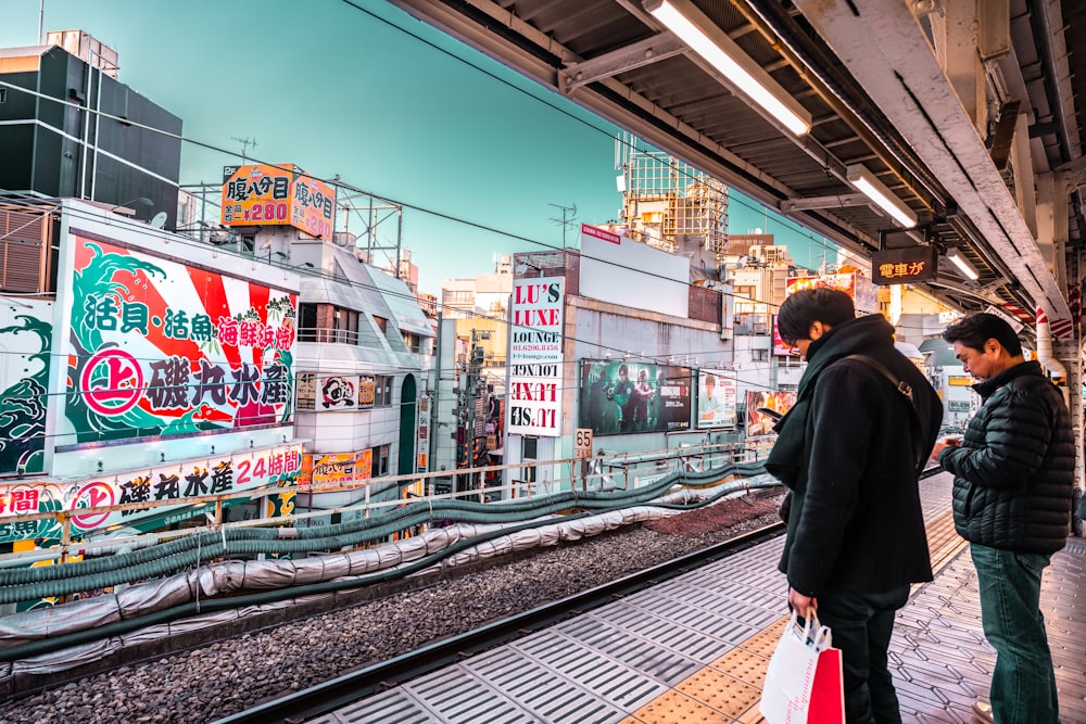 two men standing on subway during daytime