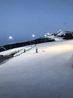 SnowArena Druskininkai illuminated at night with skiers and snowboarders on the slopes