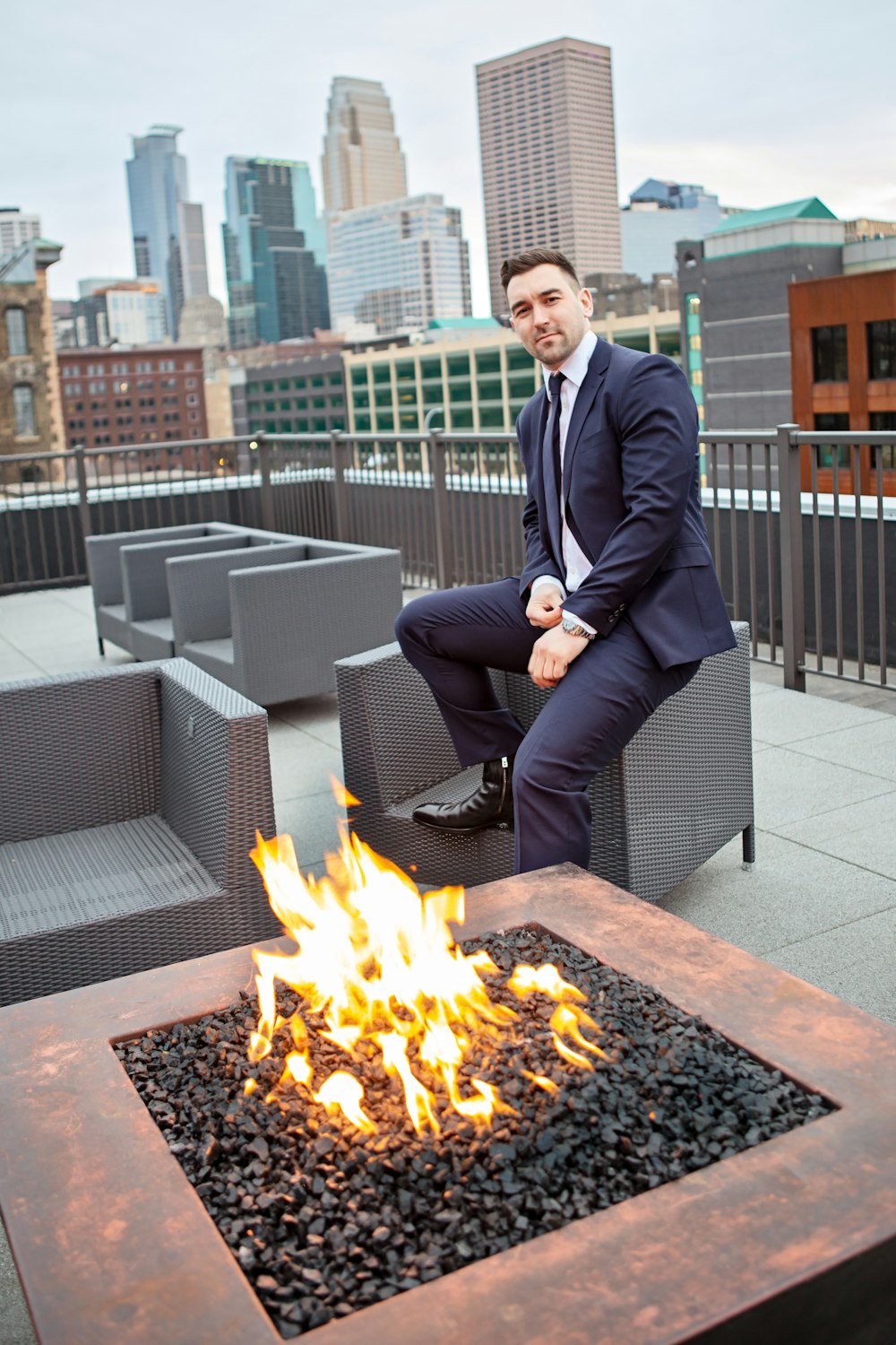 sitzender Mann im blauen Mantel neben gelbem Feuer