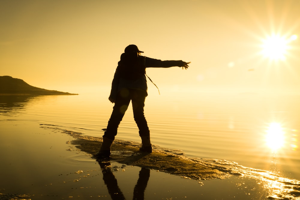 a person standing on a beach at sunset