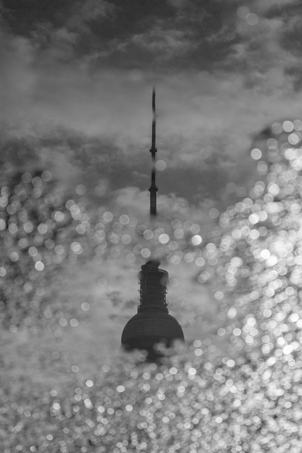 a black and white photo of a tower in the water