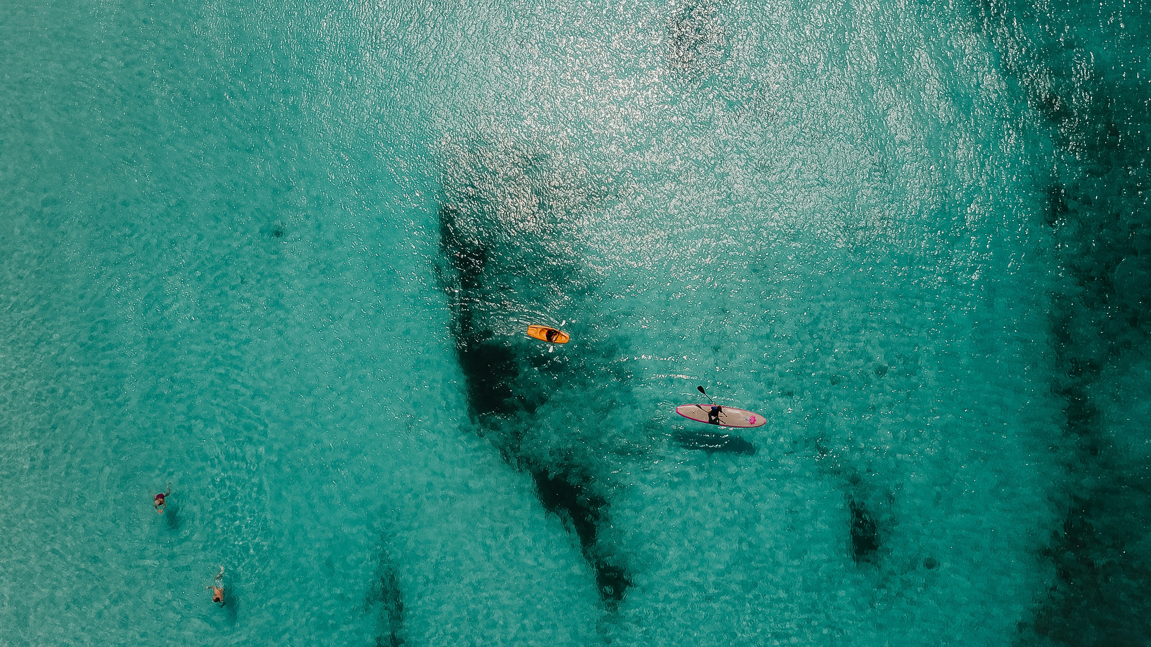 Luftaufnahme einer Person, die auf orangefarbenen Kajakbooten im mittleren Ozean fährt