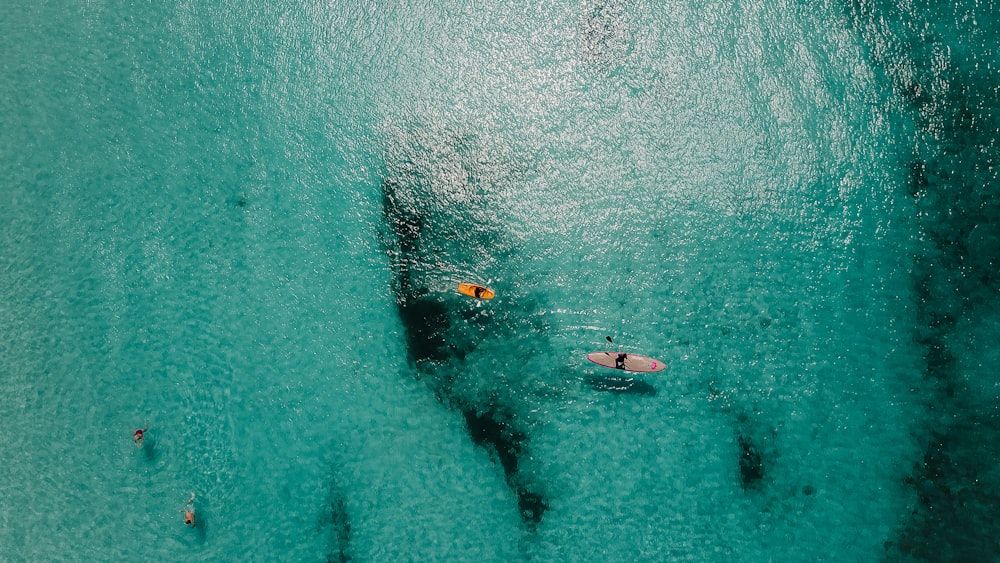 aerial view of person riding on orange kayak boats in the middle ocean