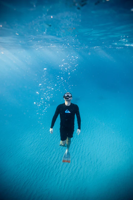 man diving under water during daytime