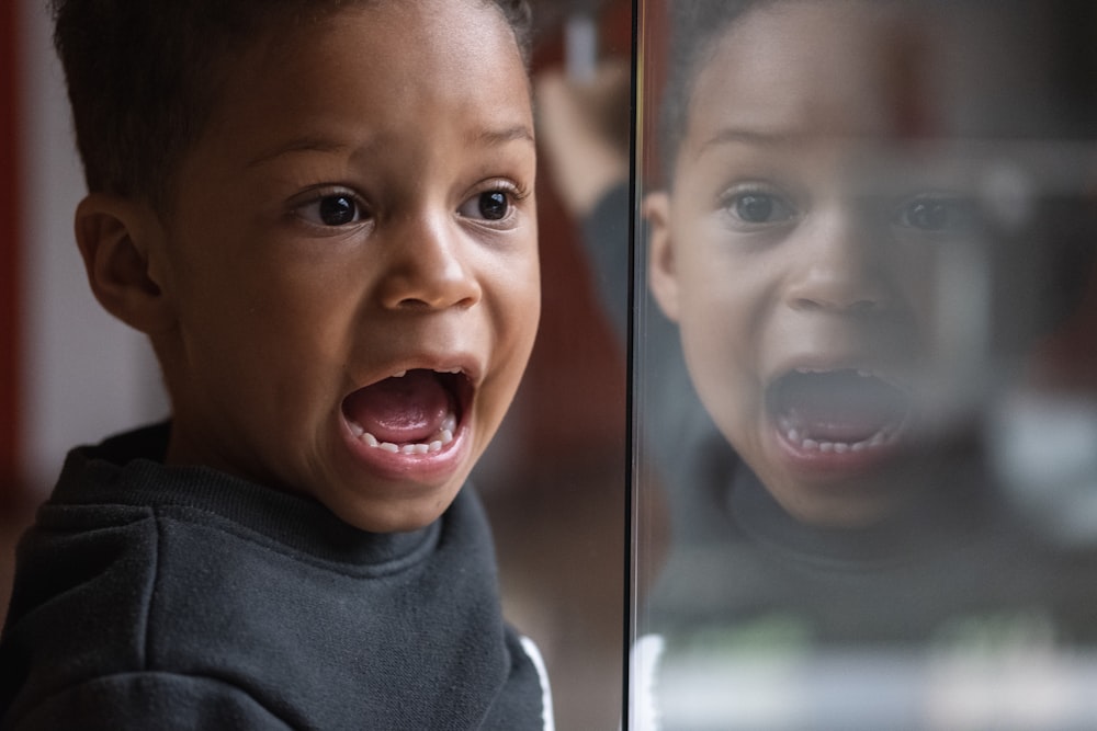 selective focus photography of boy wearing black crew-neck top with mouth open