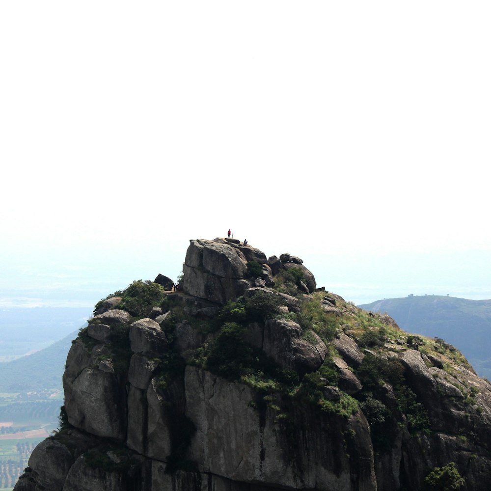 people standing in mountain overlooking grass fields during daytime