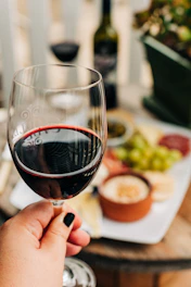 person holding half empty wine glass near table