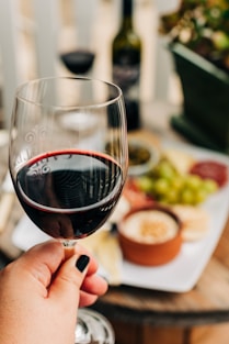 person holding half empty wine glass near table