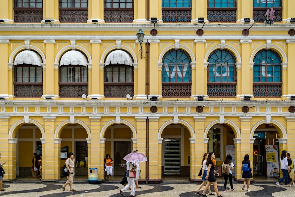 people near yellow building during daytime