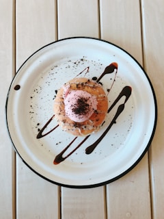 A chef carefully plating a dessert, with a drizzle of chocolate sauce and a sprinkle of powdered sugar.