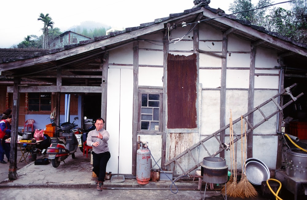 man standing beside white wooden house