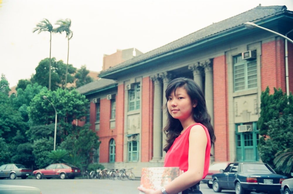 woman in red sleeveless top near building