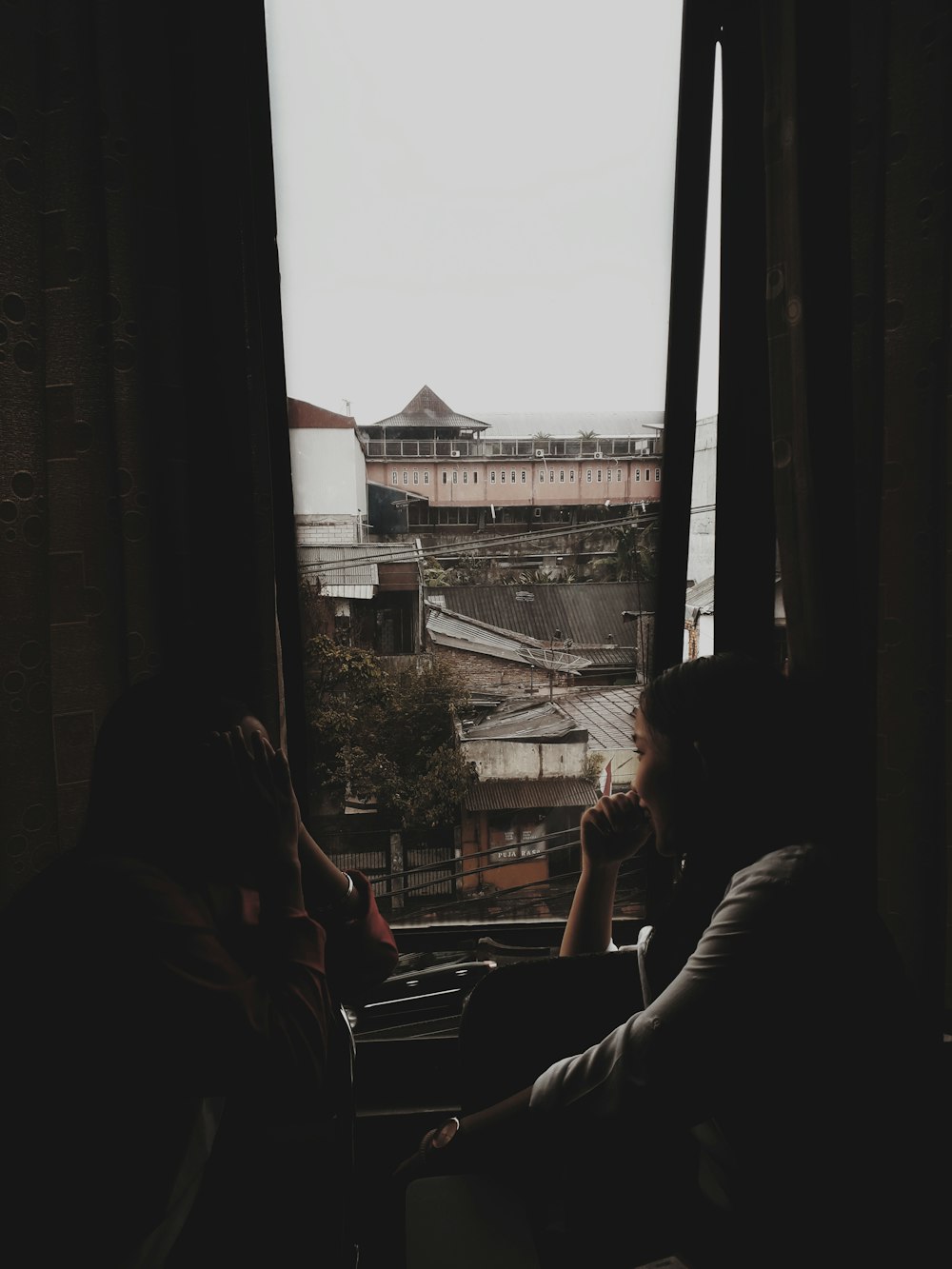 a couple of people sitting next to each other near a window