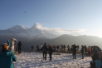 A vibrant group photo of travelers smiling against the snowy peaks of Manali at sunrise