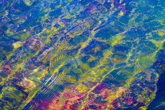 A serene water ripple glowing with vibrant cyan and magenta light waves.