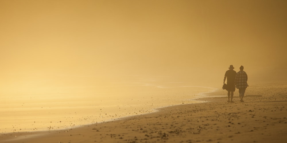 two person walking on shore