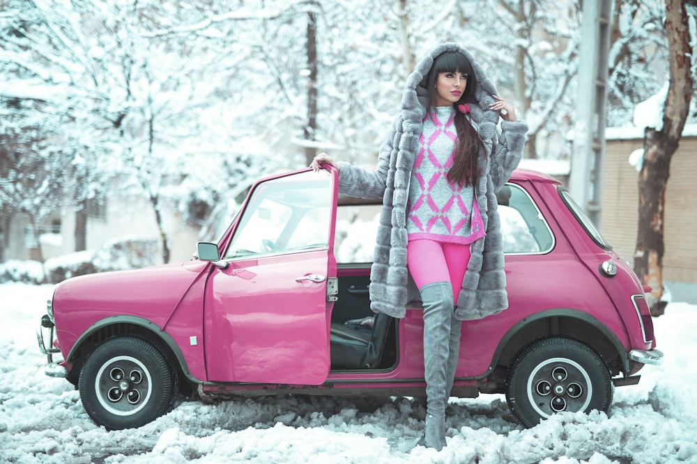 unknown celebrity standing beside pink car outdoors