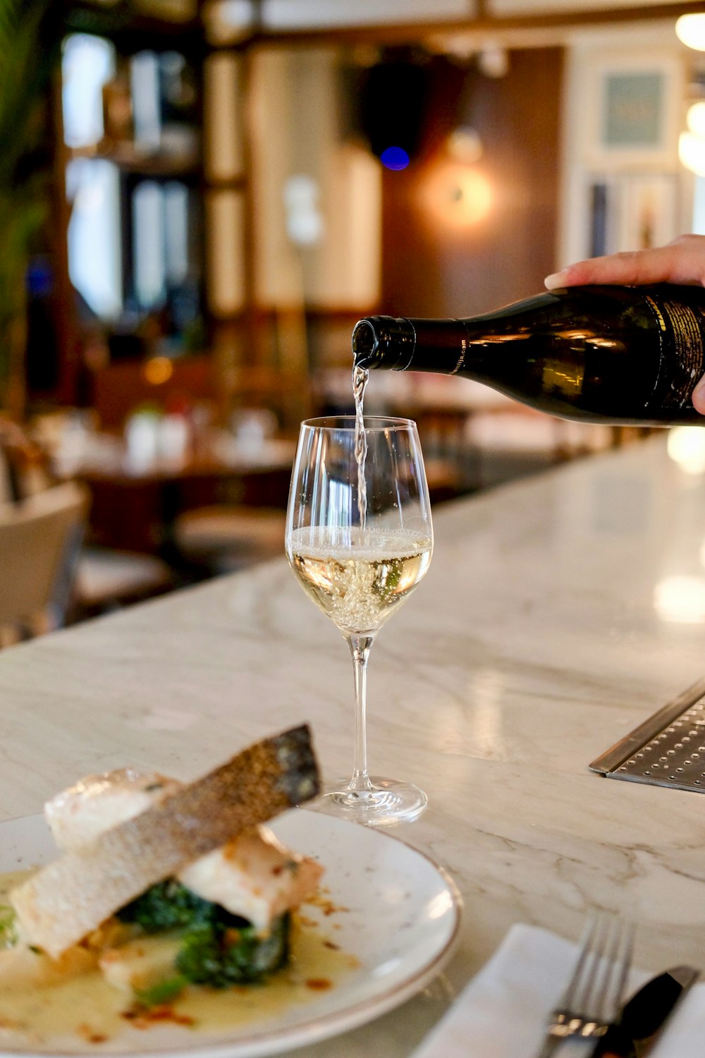 person pouring liquid in clear wine glass