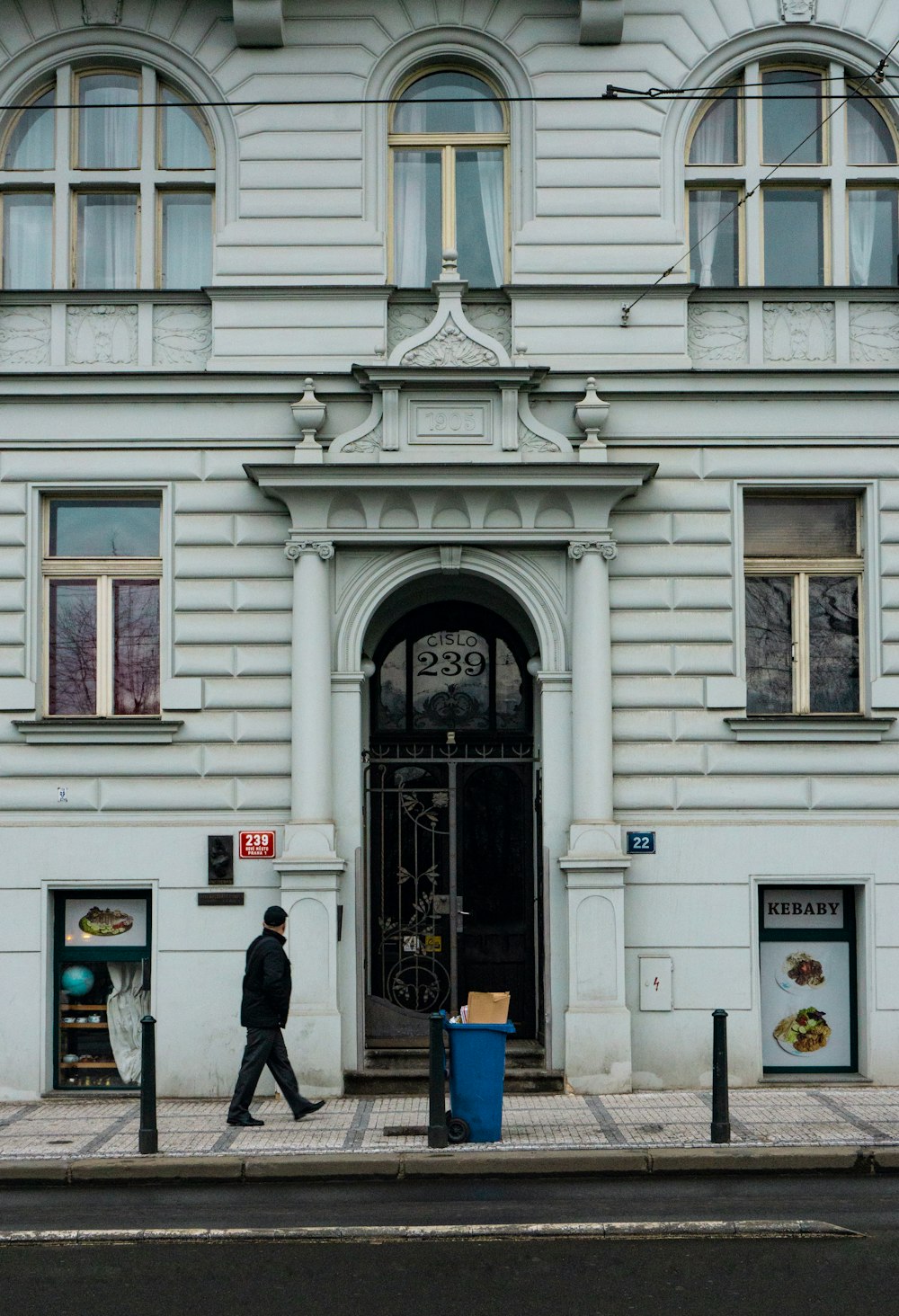 a man walking past a tall white building