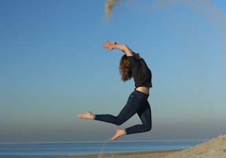 woman jumping on shore during daytime