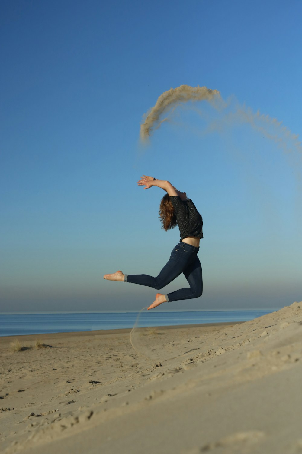 mulher pulando na costa durante o dia