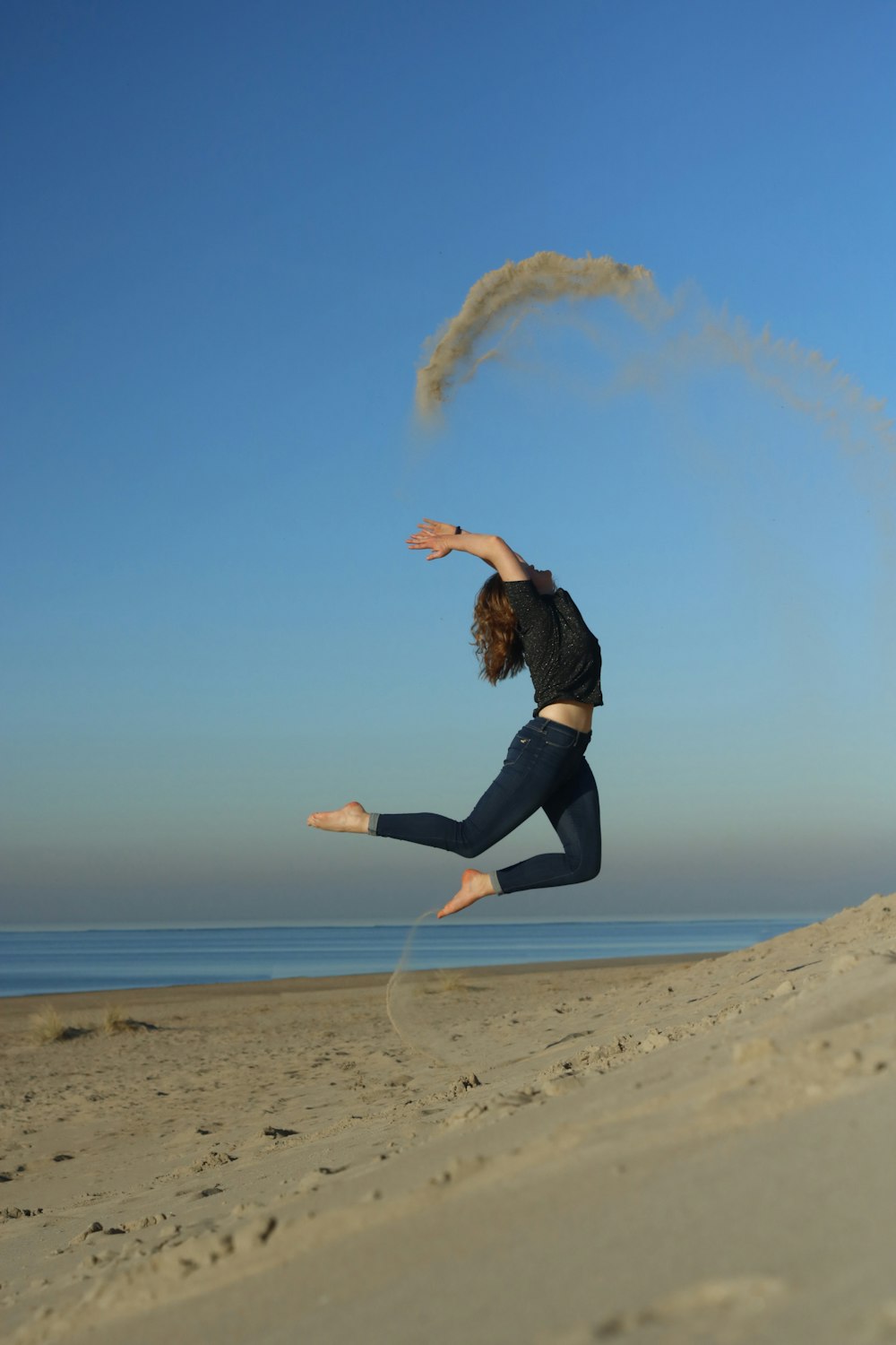 woman jumping on shore during daytime