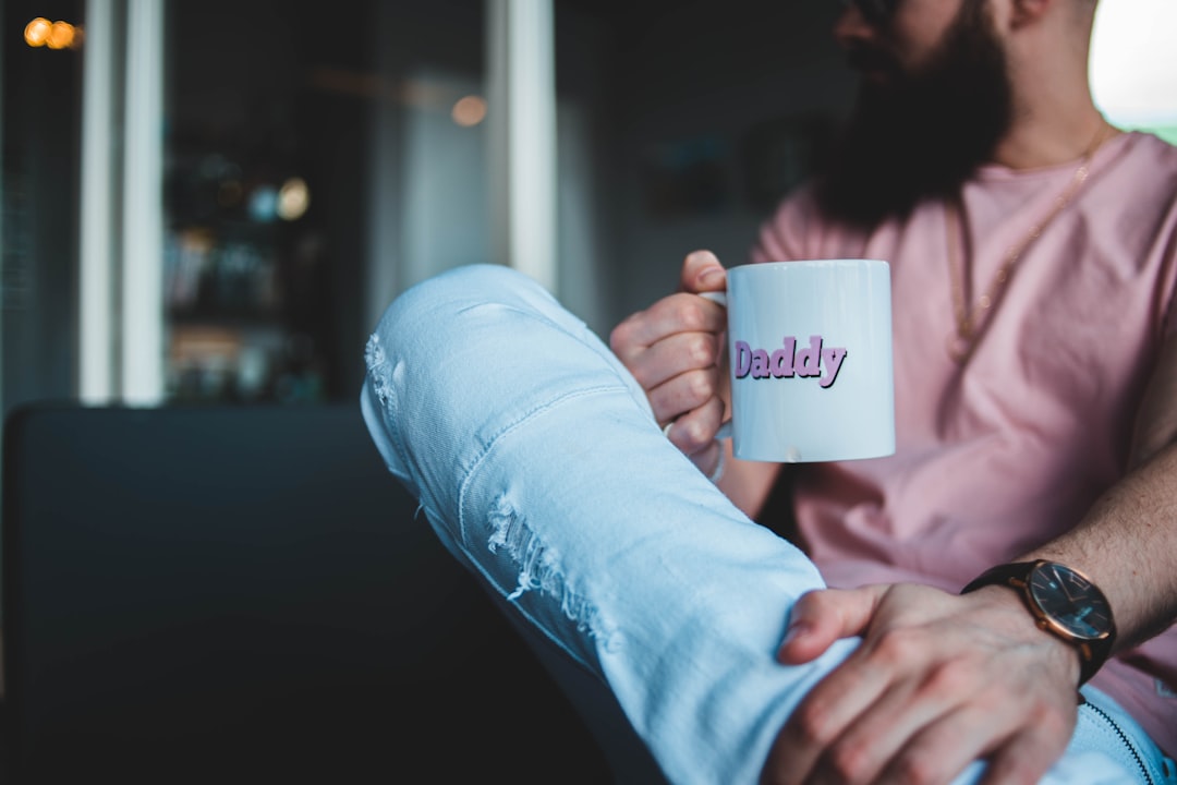 person holding white and pink Daddy-printed mug