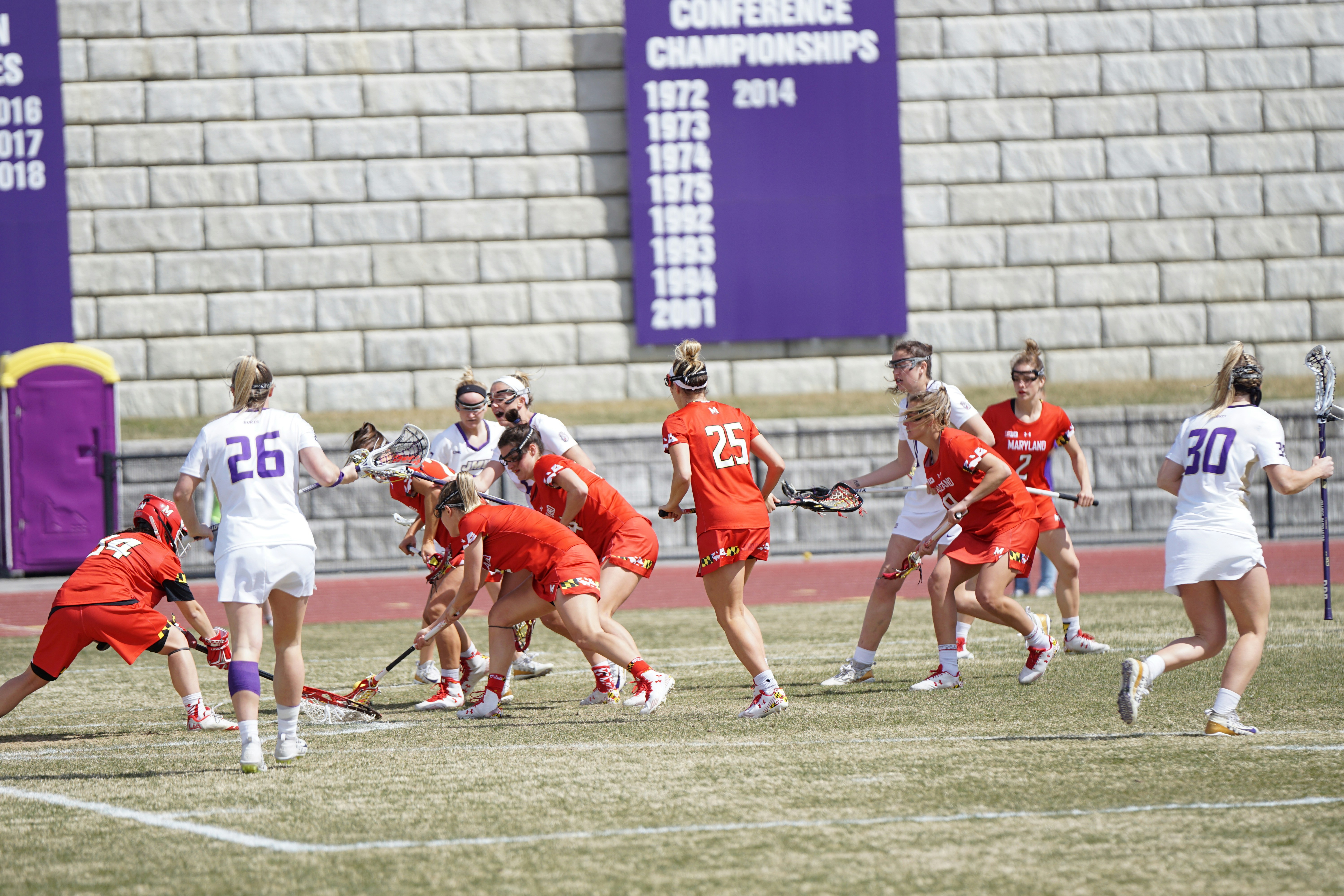 sekelompok wanita bermain lacrosse di siang hari