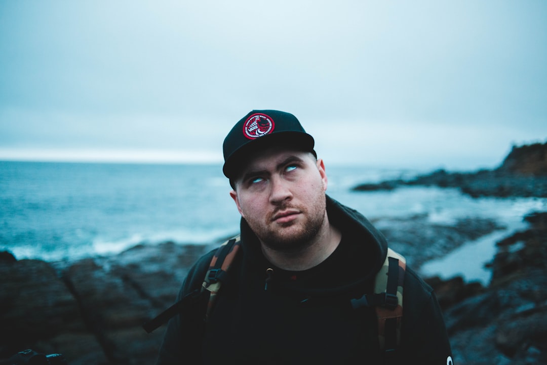 man wearing black hooded jacket and black cap