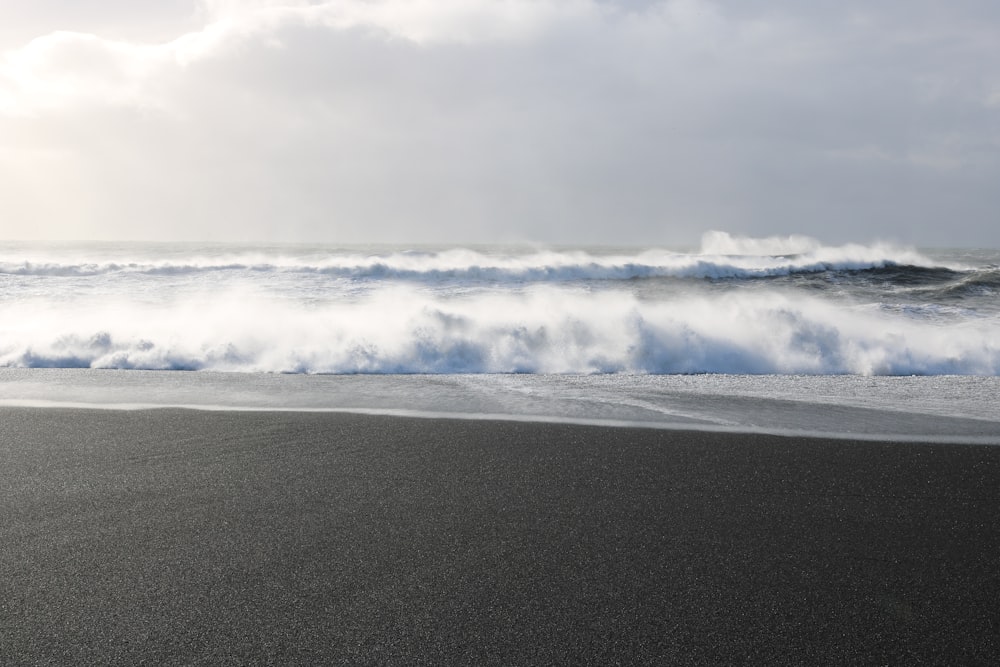 seashore with big waves under cloudy sky