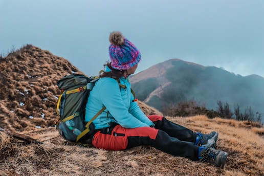 woman sitting on brown soil looking on brown mountain