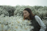 A youthful woman enjoying a fresh scent outdoors surrounded by blooming flowers.