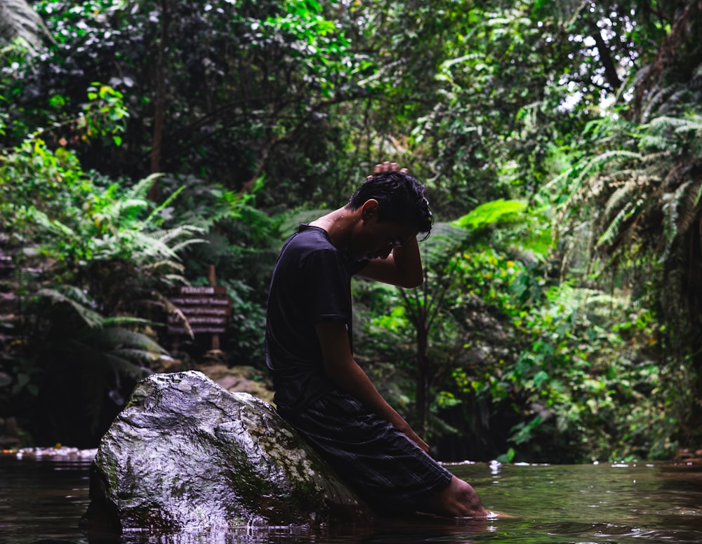 uomo in camicia nera e pantaloncini dall'acqua