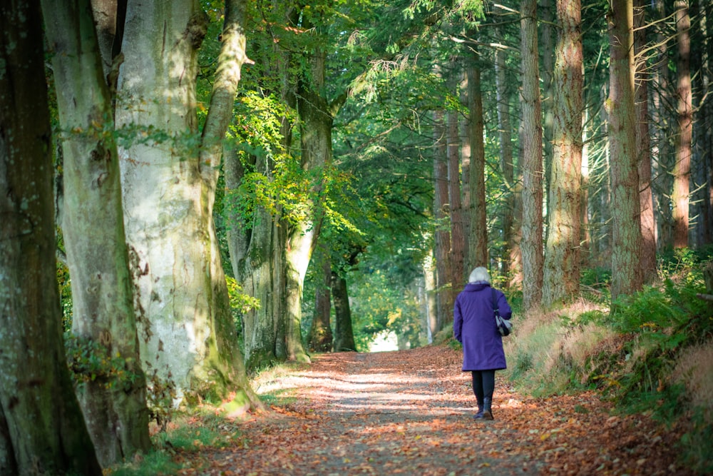 woman walking under green trees