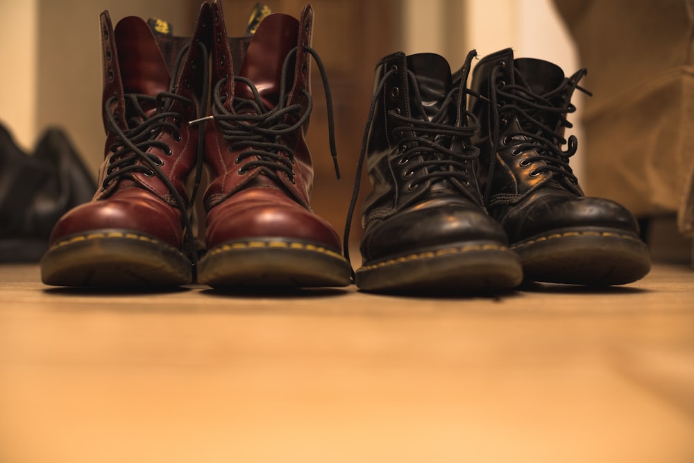 two pair of black and brown leather work boots on brown surface