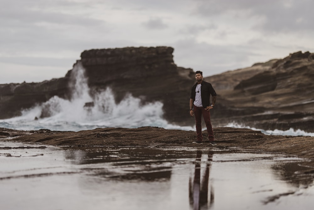 man standing on dirt near water wave