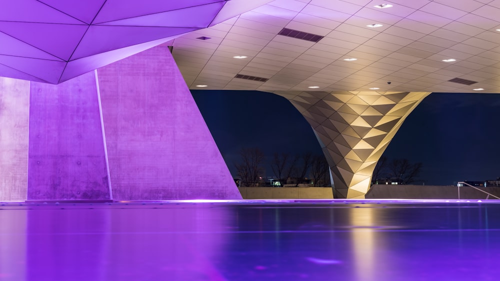 a large building with a purple lit pool in front of it