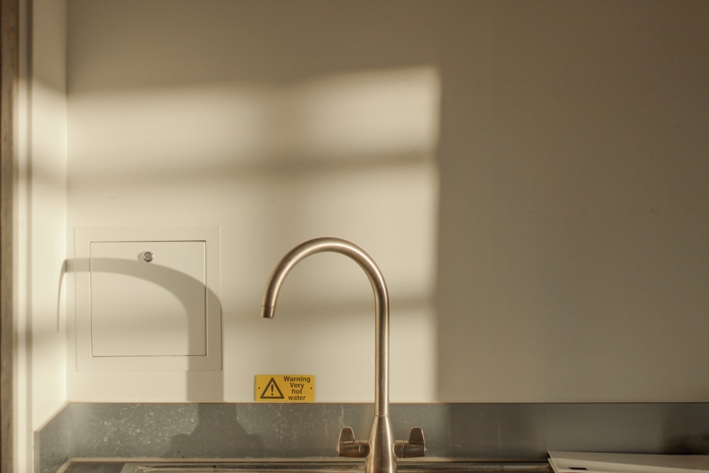 turned off faucet on sink with shadow on wall