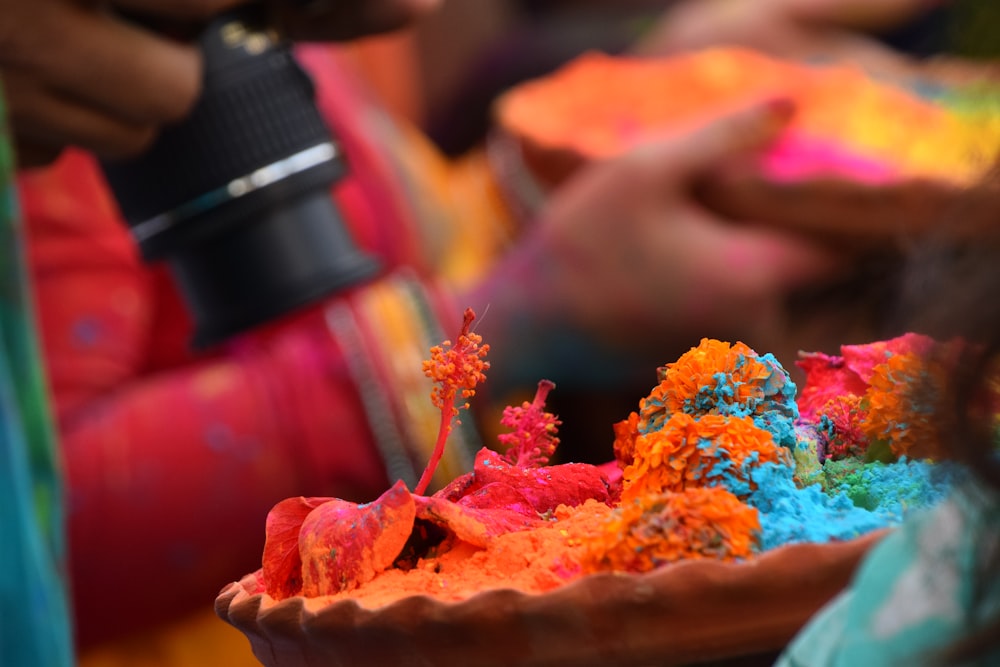 a woman holding a bowl filled with colorful powder