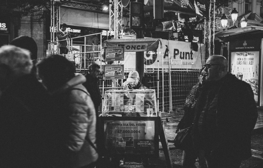 grayscale photography of man and woman walking side by side near stall