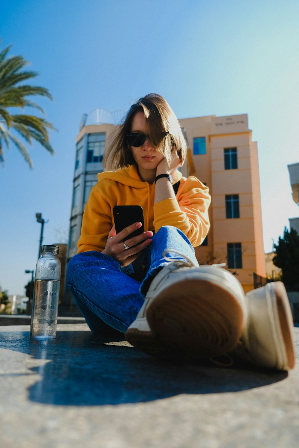 woman sitting on ground near building under blue sky