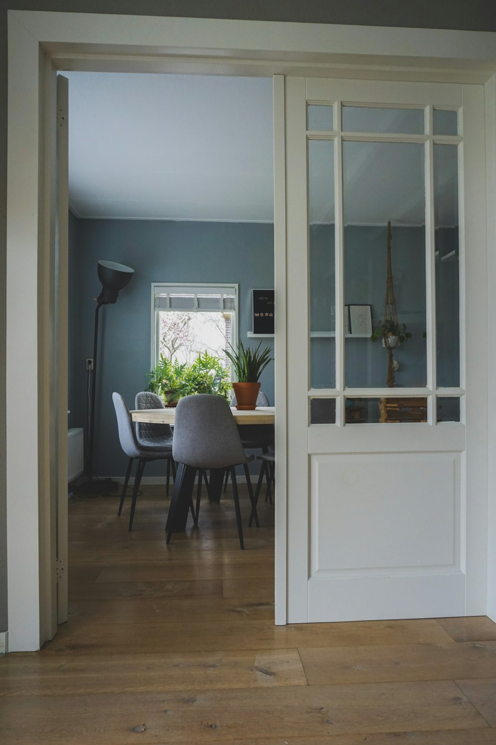 opened white wooden door through room with table and chairs