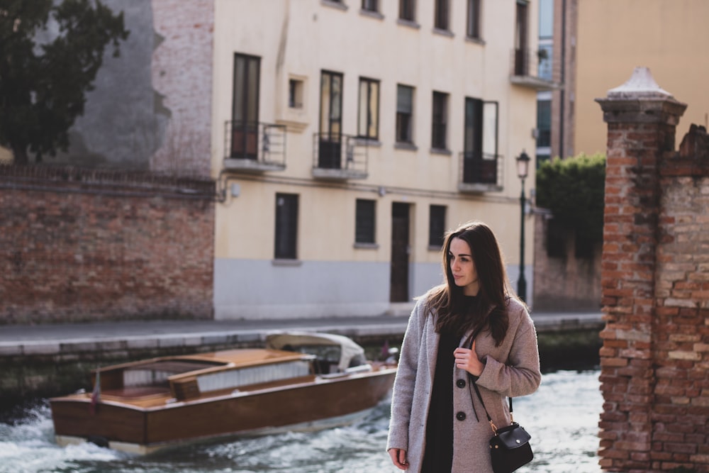 woman standing beside brown concrete brick wall