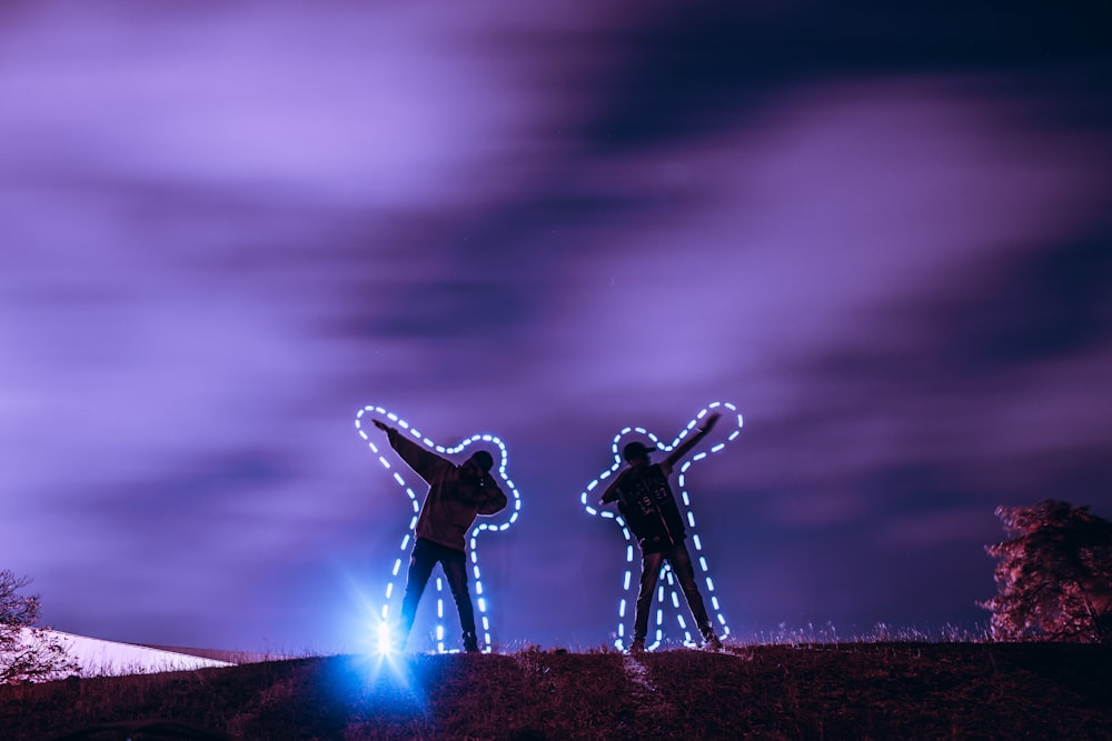 silhouette of two men standing and raising arms on their side