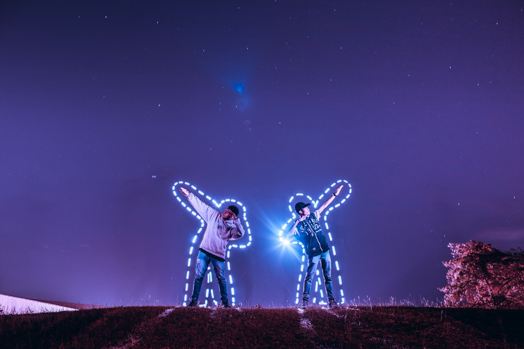 two men standing on hill under starry sky