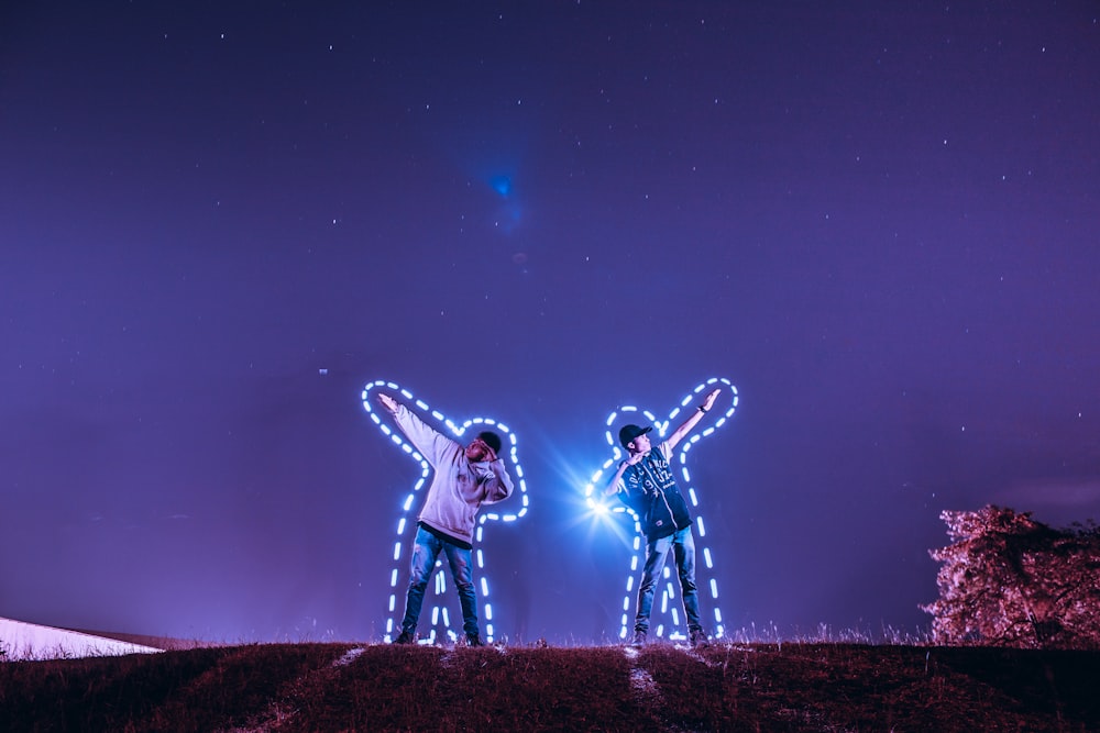two men standing on hill under starry sky