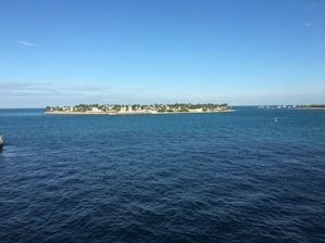 A panoramic view of an idyllic island with sandy beaches and palm trees under a blue sky.