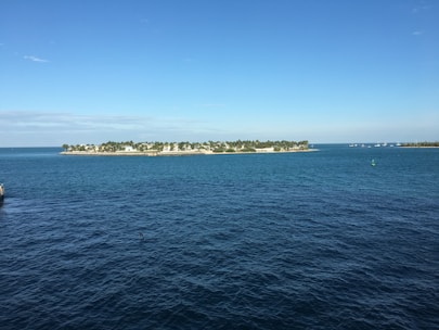 A panoramic view of an idyllic island with sandy beaches and palm trees under a blue sky.